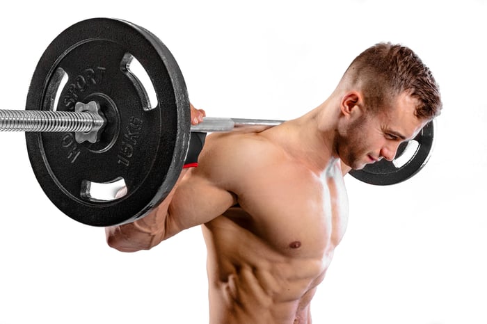 Man traint met halterstang en zwarte 15 kg schijven van Hop-Sport