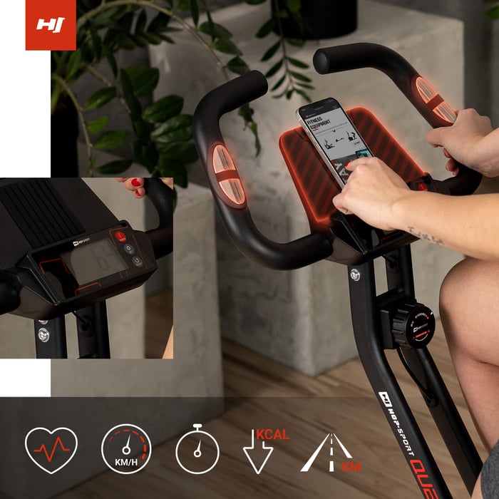 Vrouw bedient trainingscomputer van de hometrainer met hartslagsensoren en tablethouder.
