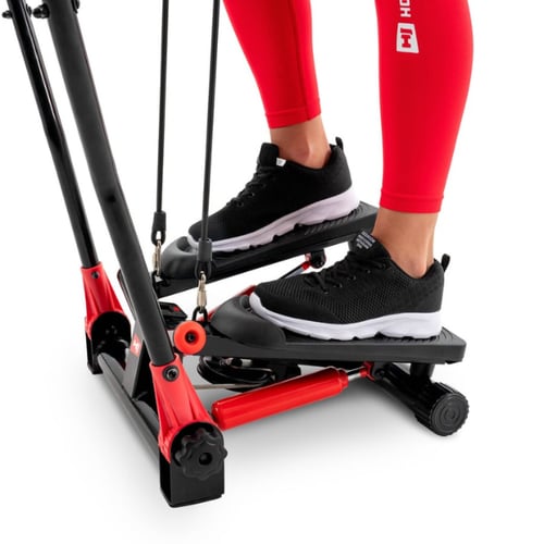 close-up van voeten in sportschoenen op de pedalen van een Hop-Sport stepper met weerstandskabels