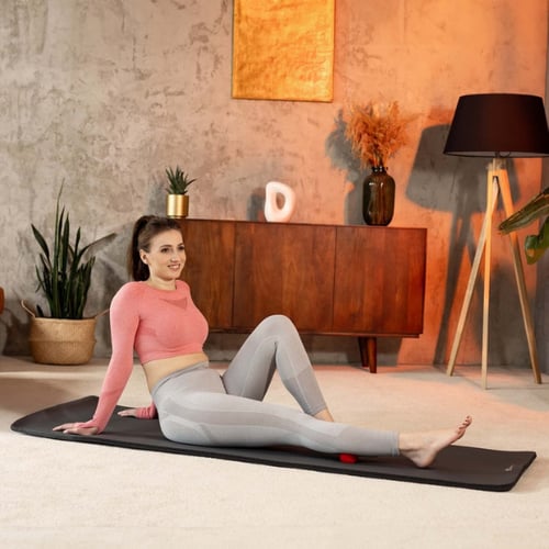 Vrouw rust uit na cooling-down-oefeningen, zittend op een yogamat