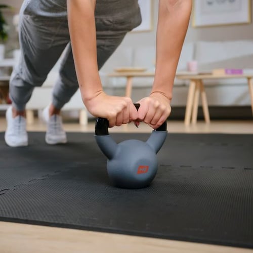 een vrouw leunt op een kettlebell