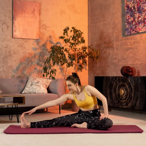 Vrouw doet cooling-down-oefeningen met een voorwaartse buiging op een yogamat