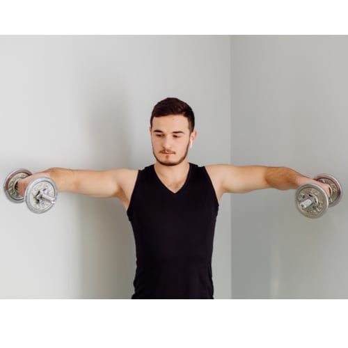 Man voert schouderoefeningen met dumbbells uit via lateral raise