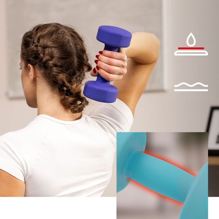 Vrouw traint met paarse neopreen dumbbell tijdens oefening binnenshuis.