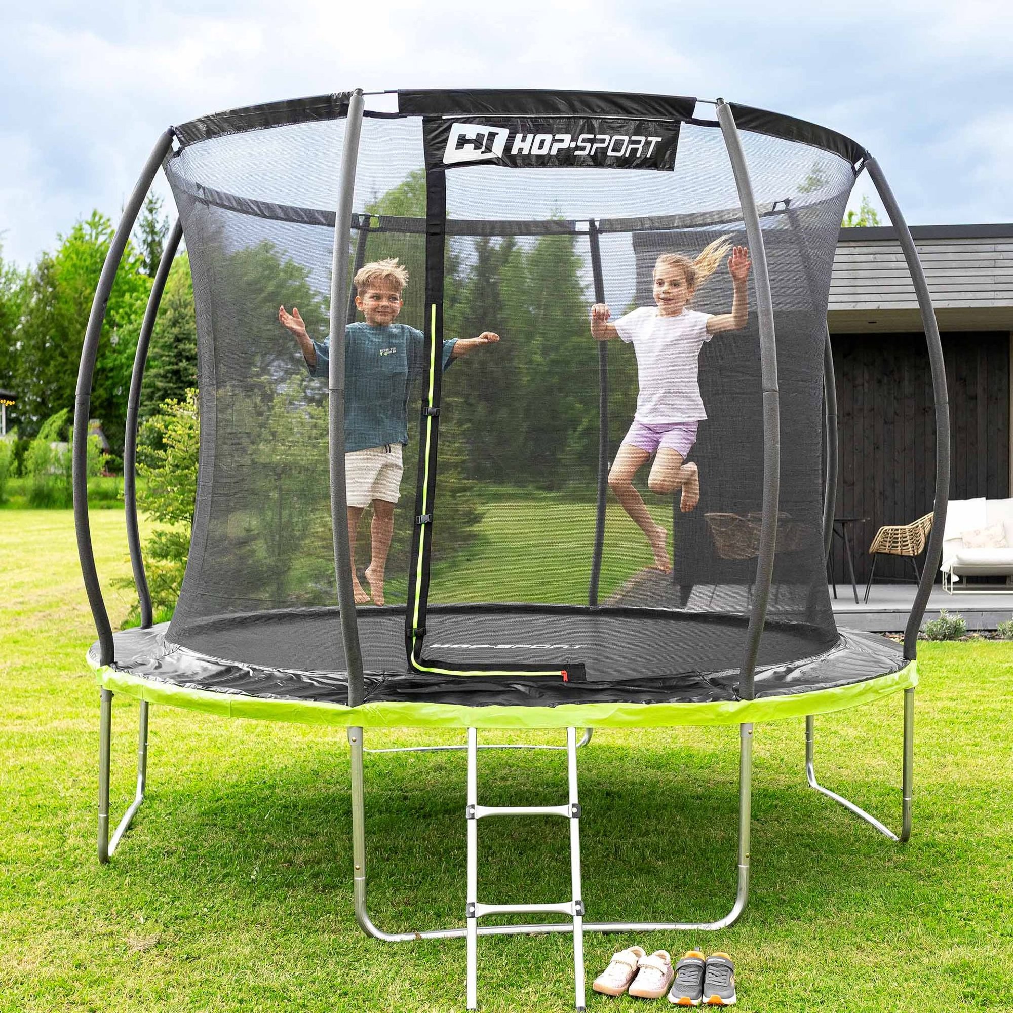 Kinderen springen op Hop-Sport trampoline met net in de tuin